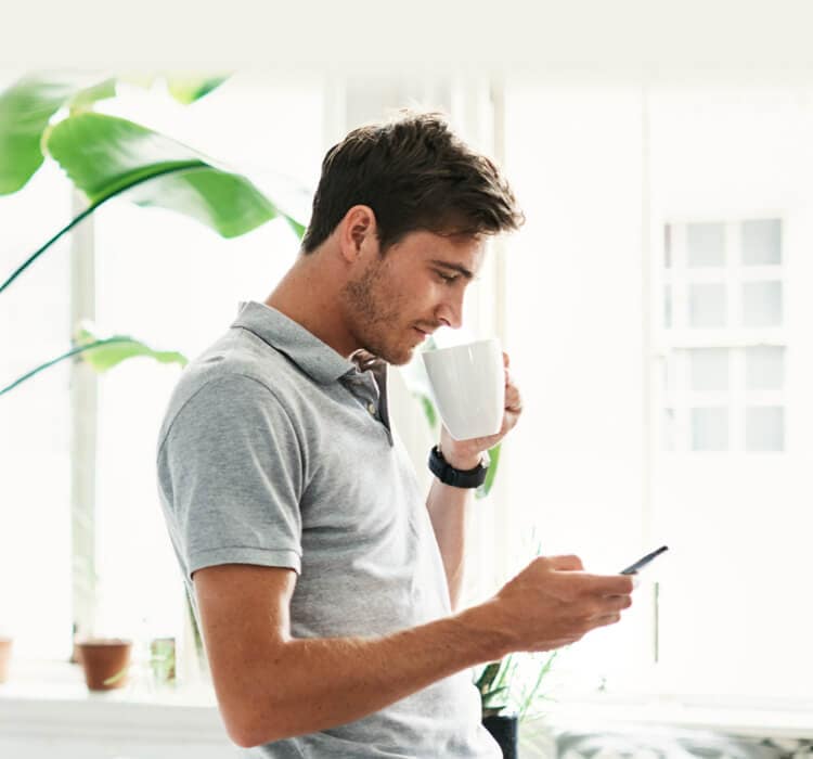 Man mit Mobiltelefon beim Kaffeetrinken