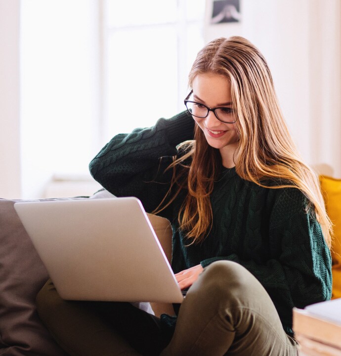 Mädchen auf dem Sofa mit Laptop beim Starten von Norton 360 Standard