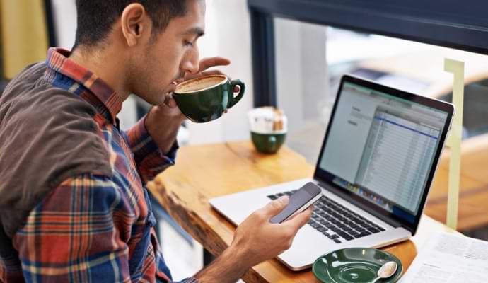 Mann mit Smartphone beim Kaffeetrinken