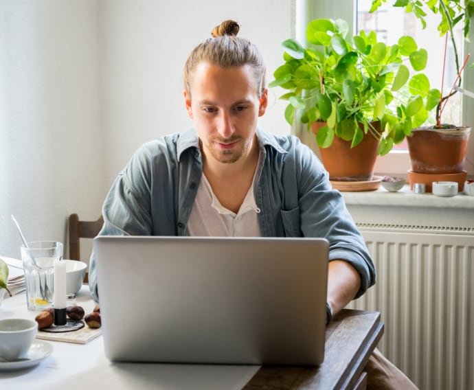 Junger Mann am Laptop in der Küche