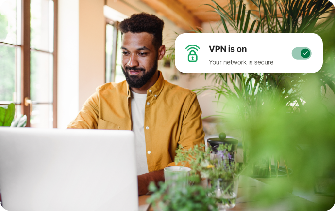 Mann, umgeben von Pflanzen, schaut auf einen Laptop und lächelt